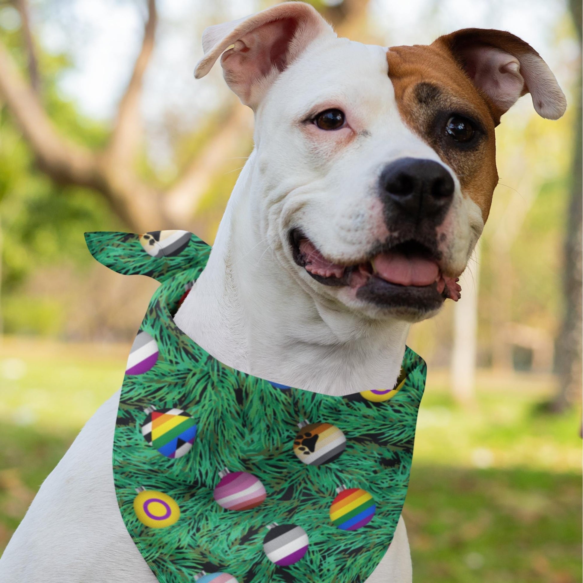 65mcmlxv white dog wearing a green Christmas tree print bandana with LGBTQI pride flag ornaments.
